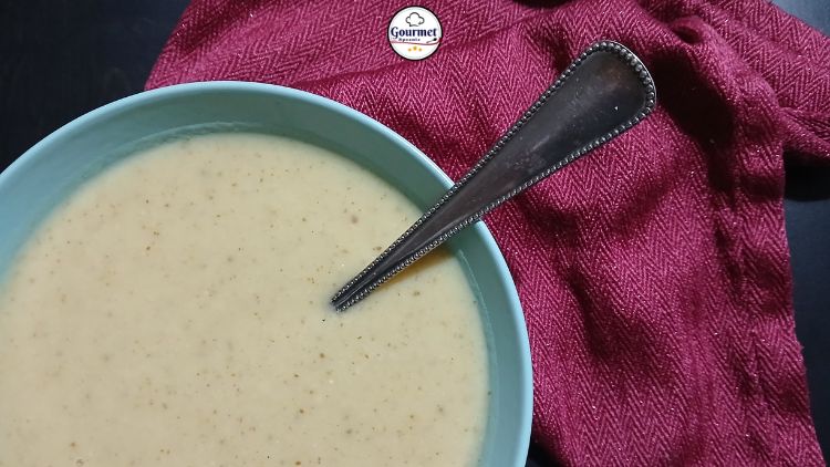 A bowl of creamy soup with a spoon inside, placed next to a textured red cloth on a dark surface—perfect for quick healthy meals or inspiring new meal prep ideas.
