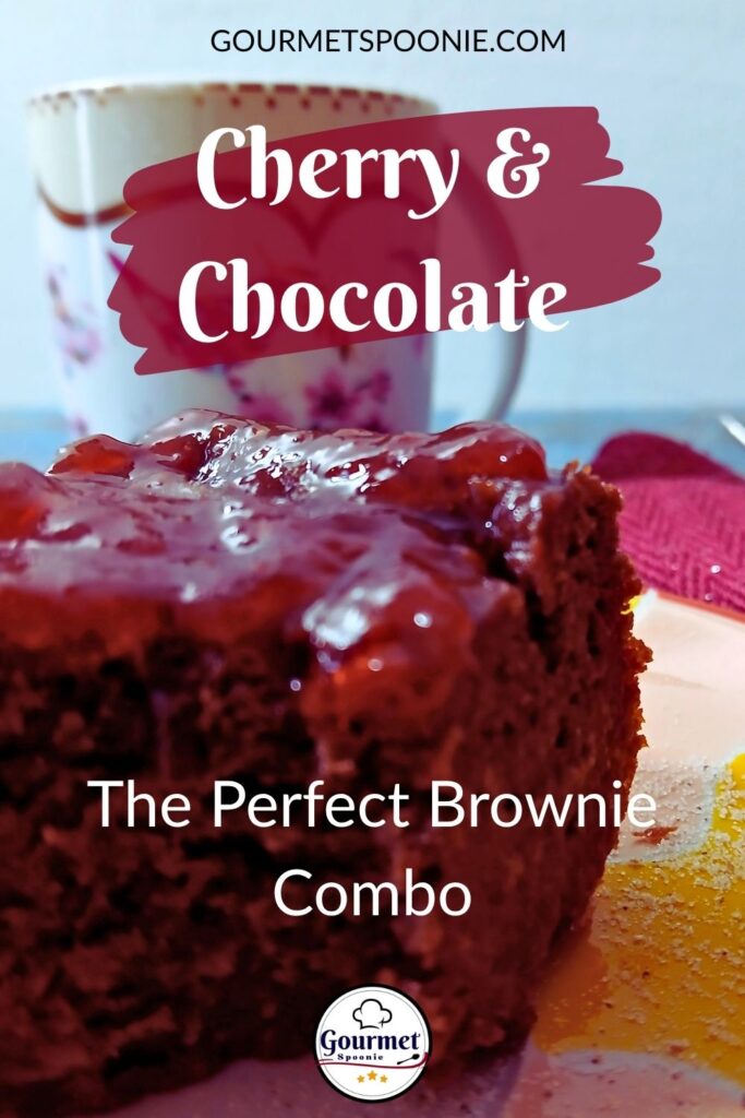 A close-up of cherry jam brownies topped with cherry sauce sits on a plate, with a floral mug in the background. Text overlays read, Cherry & Chocolate: The Perfect Brownie Combo. Try this energy-friendly recipe for your next treat!.