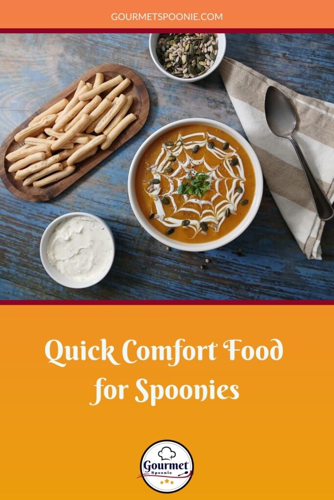 A bowl of soup with a creamy spiderweb design, surrounded by breadsticks, a bowl of dip, and seeds on a blue wooden table. Text: Quick Comfort Food for Spoonies—perfect for your emergency meal ideas. Gourmet Spoonie.