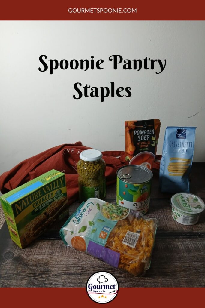 A group of spoonie pantry staples—granola bars, canned peas, pumpkin soup, breadsticks, canned tomatoes, pasta, and vegetable spread—arranged on a dark wooden surface with the text Spoonie Pantry Staples.
