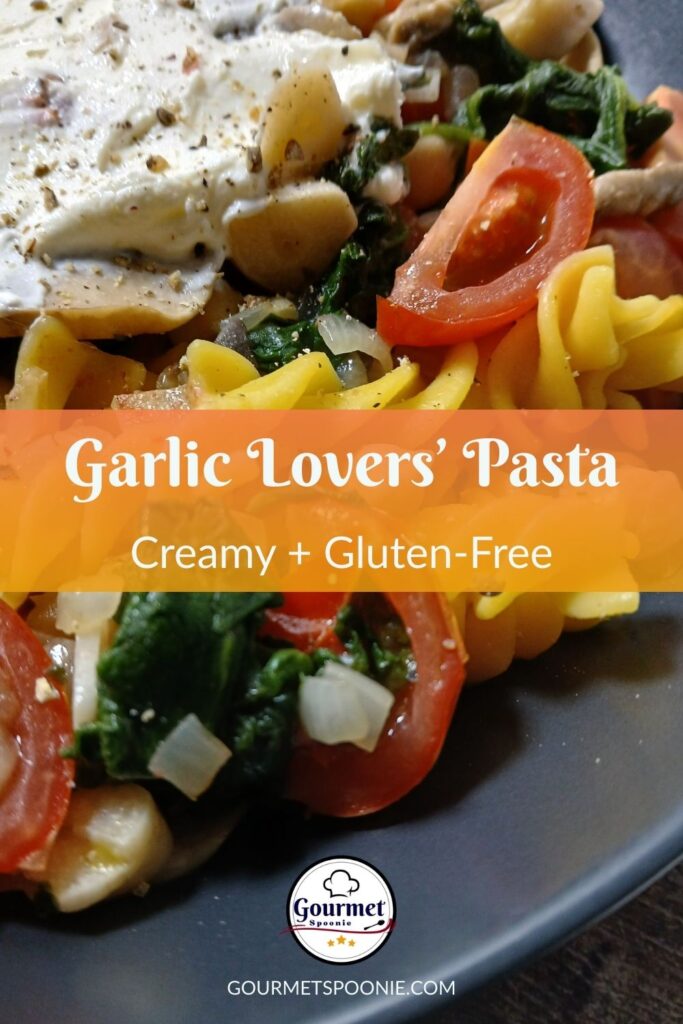 Close-up of Garlic Lovers’ Pasta featuring tomatoes, spinach, onions, and a creamy sauce on a dark plate. Overlaid text reads, Garlic Lovers’ Pasta - Creamy + Gluten-Free. Logo for Gourmet Spoonie at the bottom.