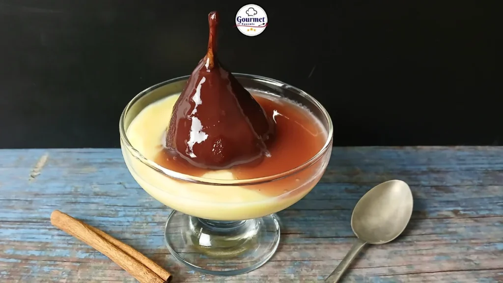 A glass dessert dish with creamy custard and whole Dutch stoofperen (stewed pears) covered in red wine sauce. A cinnamon stick and spoon lie beside it on a rustic blue wooden surface, with a black background and a Gourmet Spoonie logo above.