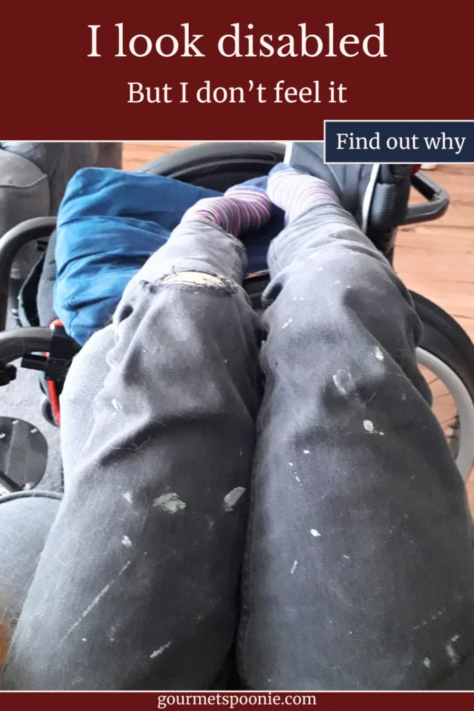Person wearing paint-splattered trousers and colourful socks sits in a wheelchair. Text above reads, I look disabled but I don't feel it. Find out why.