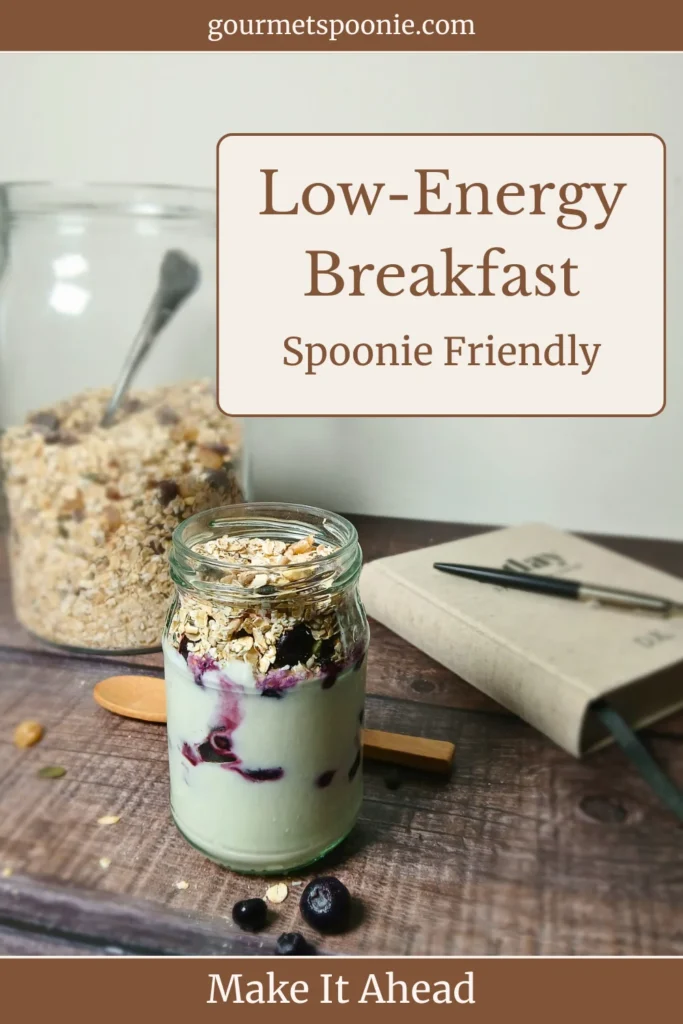 Single yoghurt parfait jar with muesli and berries on a rustic surface, styled as a simple low-energy breakfast option.