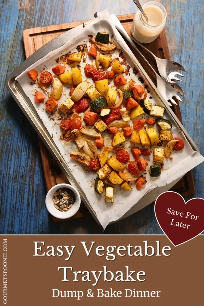 Overhead view of a roasted vegetable traybake with potatoes, carrots, courgette, and cherry tomatoes in a baking tray