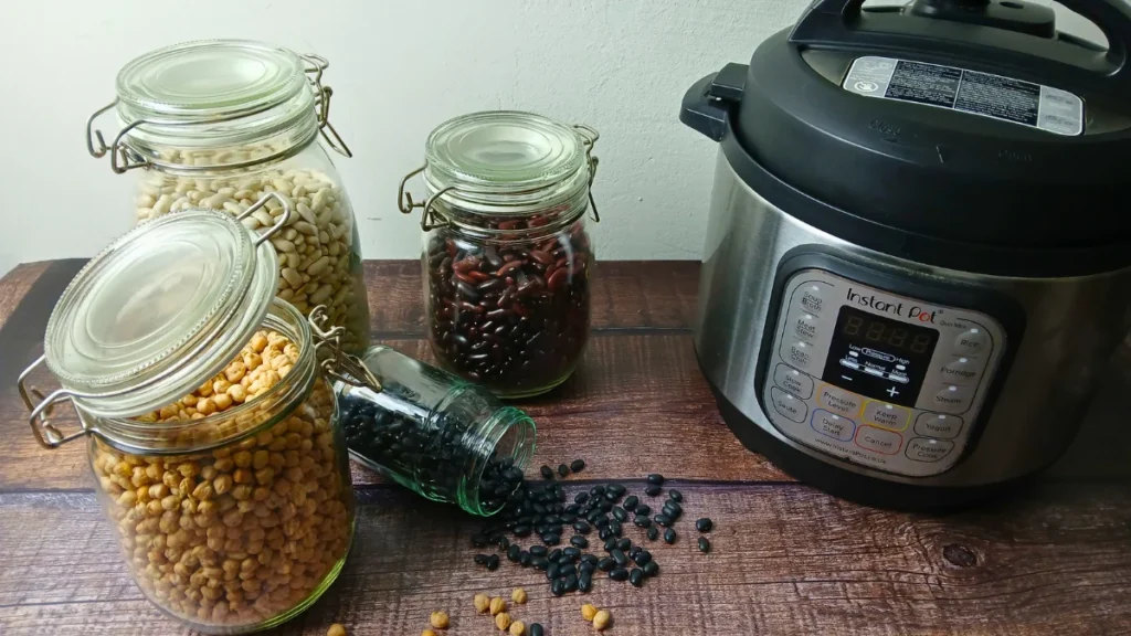 instant pot and jars of dried beans on wooden table