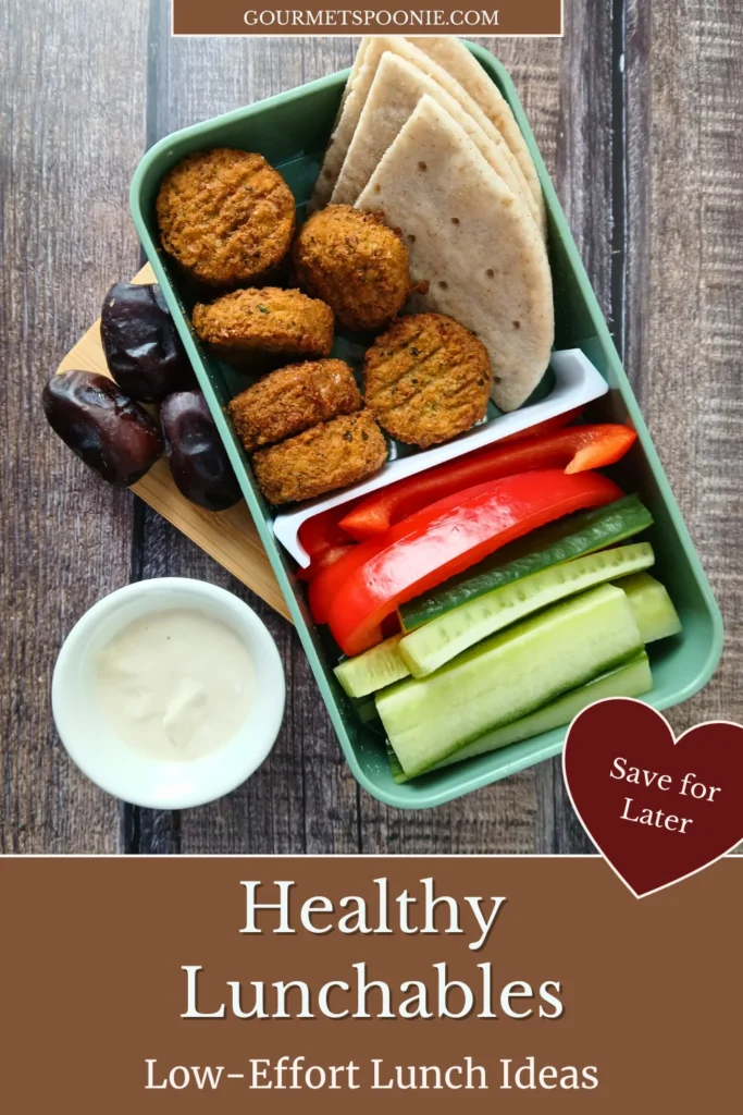 Low-effort healthy lunchables in a bento box with gluten-free flatbread, falafel, and pre-cut vegetables for easy snacking.