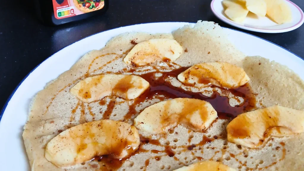 Gluten-free vegan Dutch pancake with apple slices and cinnamon, lightly browned