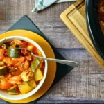 Bowl of slow cooker ratatouille made with courgettes, peppers, potatoes, tomatoes, and tofu.