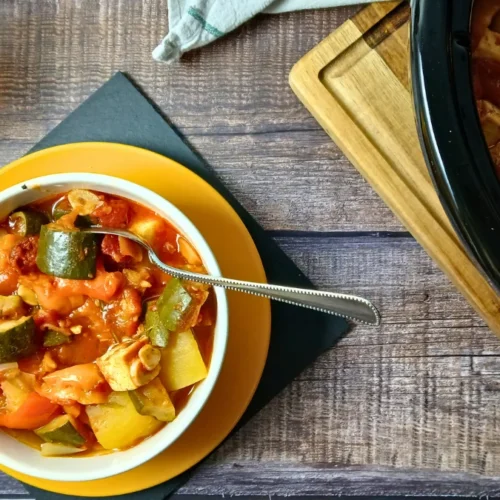Bowl of slow cooker ratatouille made with courgettes, peppers, potatoes, tomatoes, and tofu.