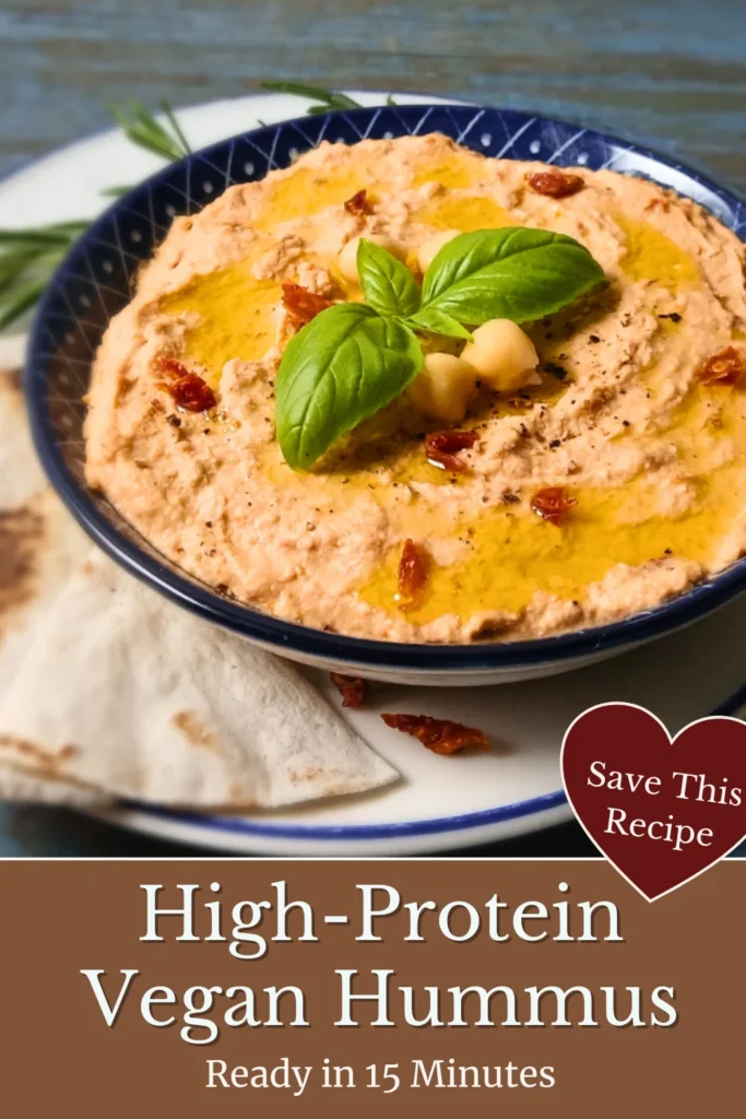 Homemade sun-dried tomato hummus topped with basil and chickpeas, served with flatbread.