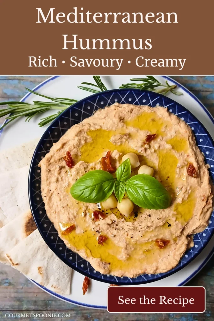 Creamy homemade sun-dried tomato hummus garnished with basil and olive oil in a blue bowl.