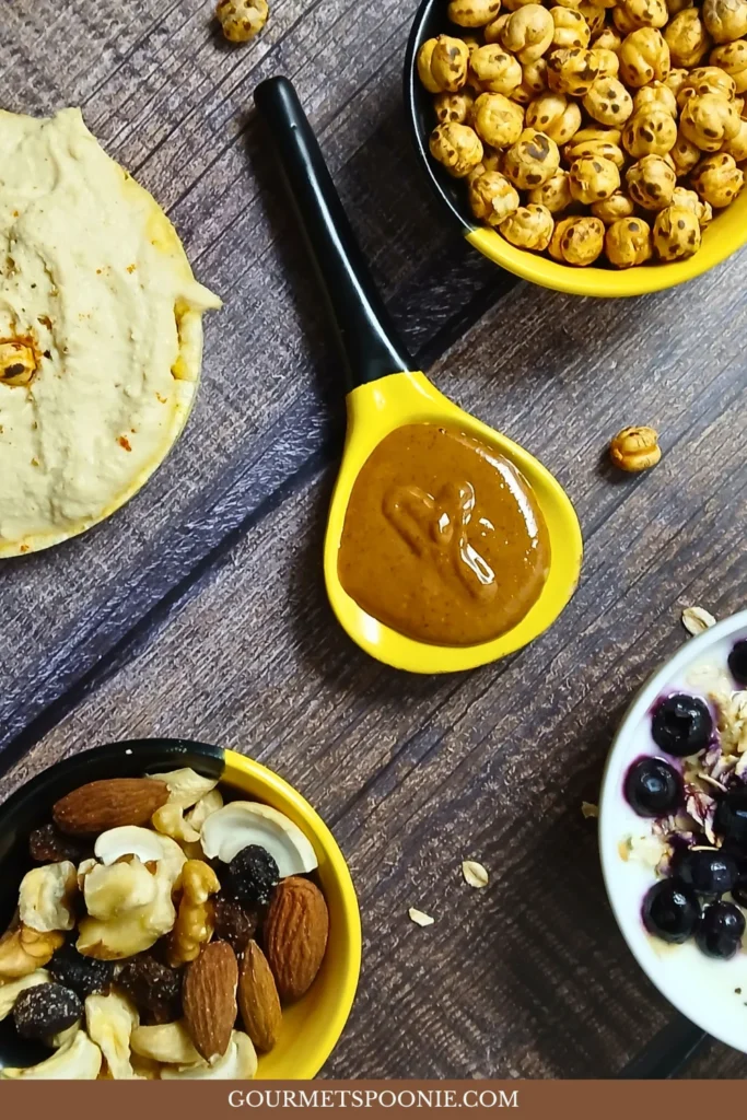 image of high-protein foods: hummus, peanut butter, toasted chickpeas, trail mix, and soy yoghurt with tahini and hemp seeds