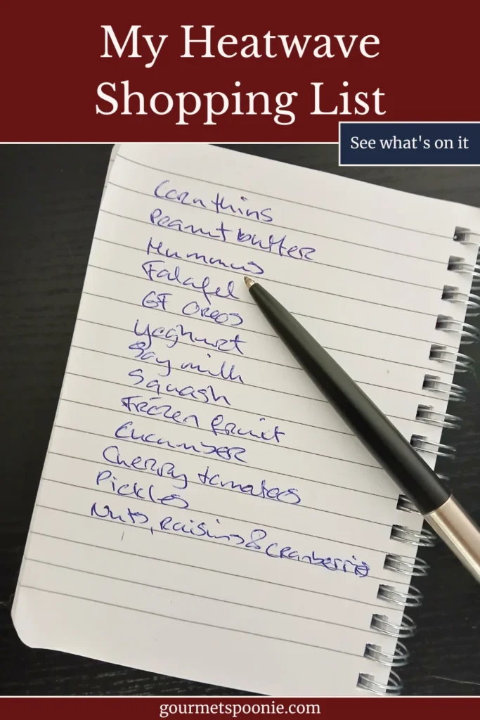 A handwritten shopping list beside a black pen on a notebook, photographed on a dark tabletop, representing planning and shopping for an upcoming heatwave.