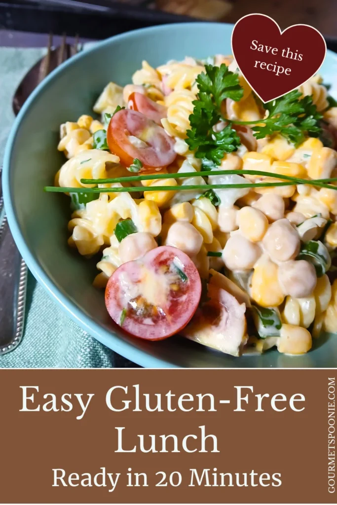 Close-up of creamy gluten-free pasta salad with cherry tomatoes, chickpeas, sweetcorn, herbs, and garlic yoghurt dressing.